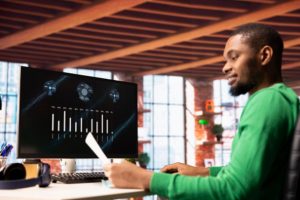 Man working at a modern office desk, analyzing financial data on a computer screen powered by Artificial Intelligence technology.
