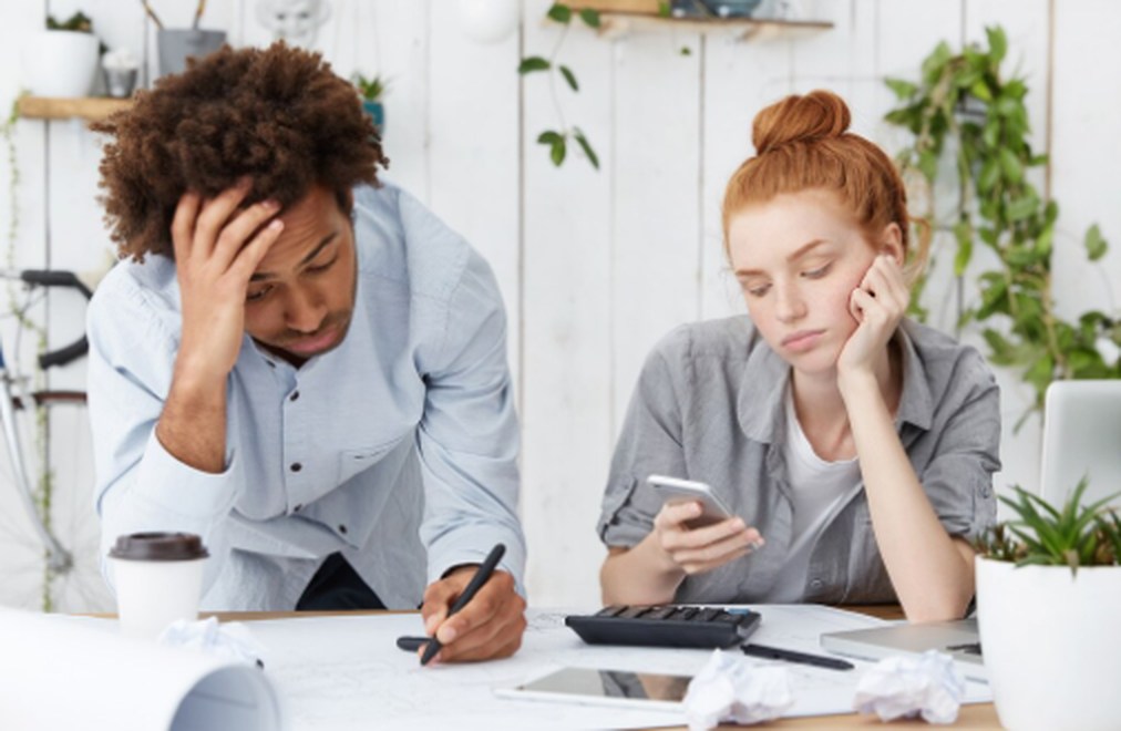 A worried couple reviewing bills and financial documents at home, considering debt restructuring options to manage payments and avoid default.
