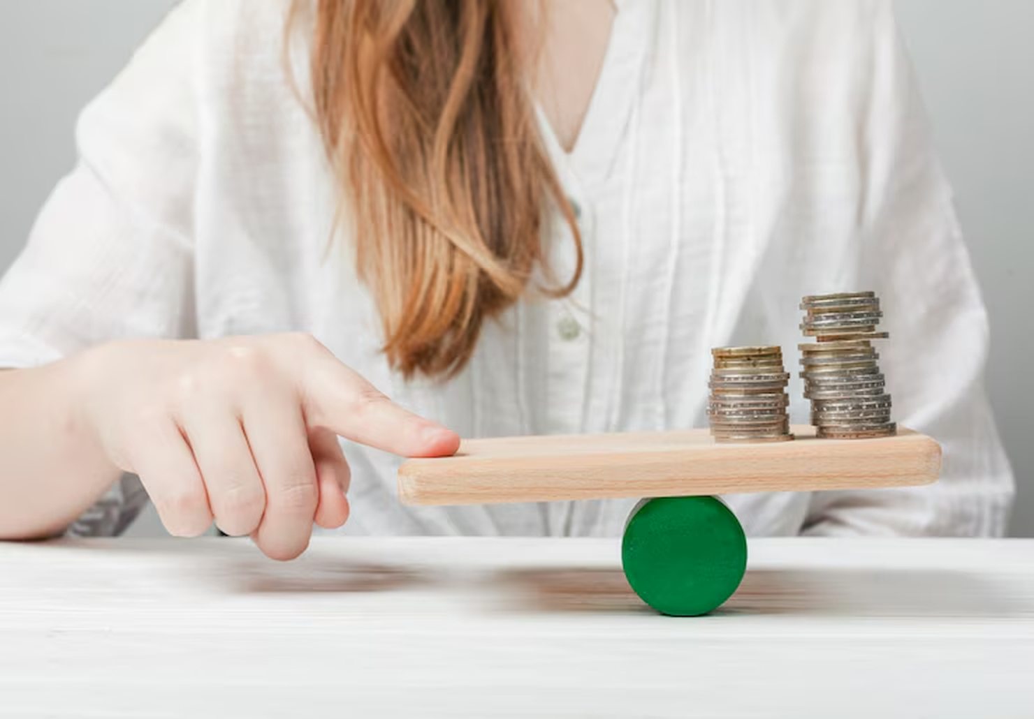 A person balancing stacks of coins on a wooden seesaw, symbolising the careful evaluation of interest rates and financial decisions to achieve stability and fairness.